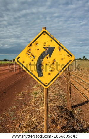 Road sign with bullet holes on farm road