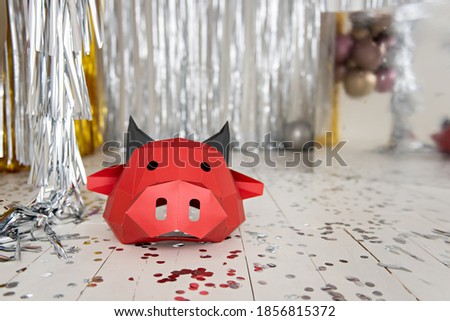 Red ox head against a background of silver, gold bokeh. Bright, shiny new year bull festive card. Christmas calendar blank, internet banner. 3D mask made of cardboard, popier Moshe. Copy space, layout