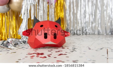 Red ox head against a background of silver, gold bokeh. Bright, shiny new year bull festive card. Christmas calendar blank, internet banner. 3D mask made of cardboard, popier Moshe. Copy space, layout