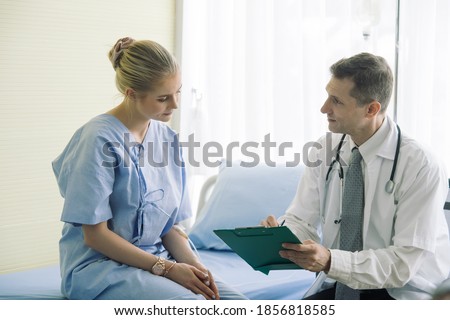 Doctors listening to his patient and taking notes at their desks in the clinic.