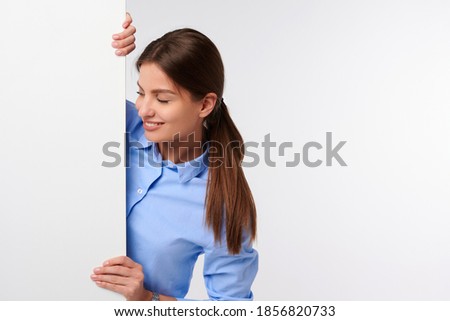 Attractive businesswoman in shirt holding white blank billboard and smiling on white isolated background
