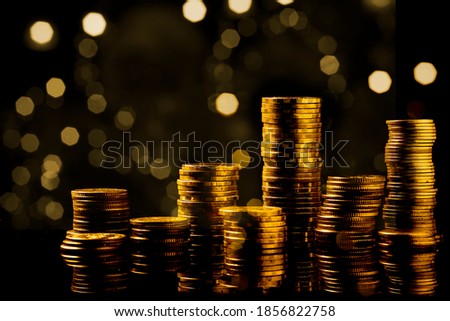 golden coins stack dramatic composition with shadow reflexing on the dark background with abstract bokeh glitter and empty space for business conceptual text