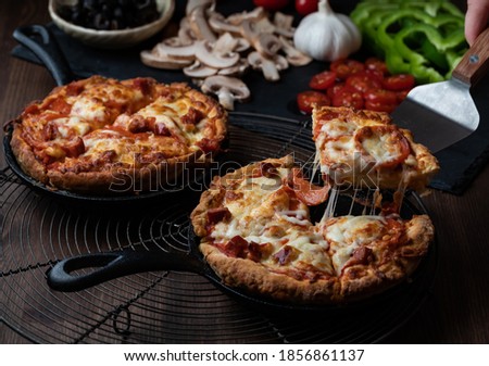 Close up of two individual deep dish pan pizzas with a slice taken out of one. Royalty-Free Stock Photo #1856861137