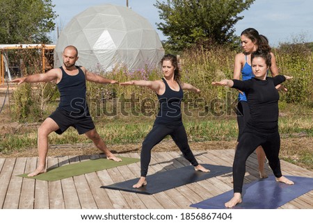 A small group of people participating in an afternoon outdoor yoga class on a wooden platform at a farm.