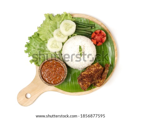 Fried chicken with ripe golden skin laid out on a wooden sheet on a white background, plus white rice, chili sauce and various vegetables, view from above. commonly used for menus and picture packs.