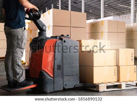 Warehouse worker working with electric forklift pallet jack unloading cardboard boxes on pallet at the warehouse.Cargo shipment boxes, Packaging, Warehousing storage. Royalty-Free Stock Photo #1856890132