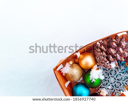 Christmas tree toys in a wooden box on white snow. Christmas holidays. New Year. Loose winter snow. New Years holidays. Winter vacation. Place for text. Greeting card. White background.
