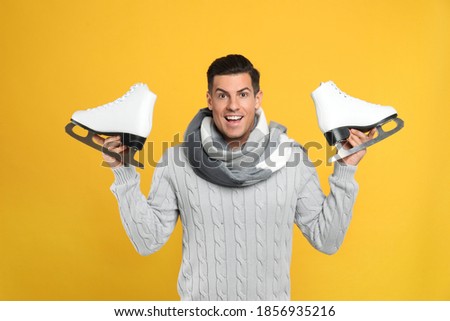 Emotional man with ice skates on yellow background