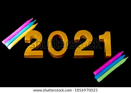 2021 made of wood and  gold painted on black background,candles and numbers placed on the backdrop,concept to New Year