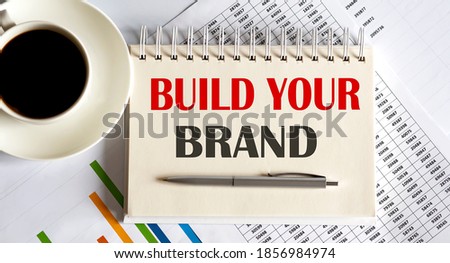 Notepad with the text Build Your Brand on light background, with coffee