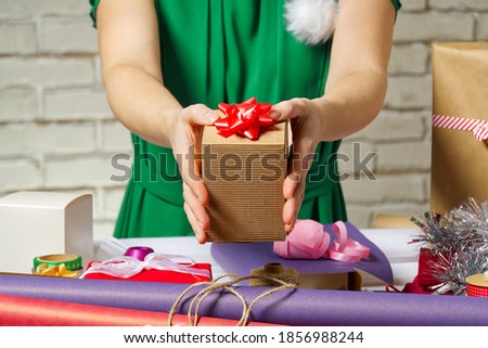 Female hands holding a small gift box wrapped in packing paper. To give and receive gifts from loved ones for christmas, valentines, birthday.