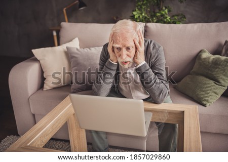 Photo of depressed pensioner wear grey cardigan sitting arms head watching modern gadget indoors house flat