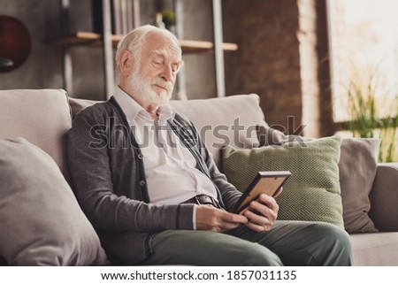 Photo of serious dreamy old man dressed white shirt sitting sofa looking photo frame inside indoors flat home house