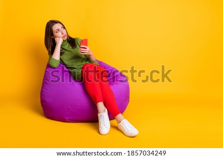 Full size photo of sad bored lady sit bean bag hold telephone wear sweater pants shoes isolated yellow color background Royalty-Free Stock Photo #1857034249