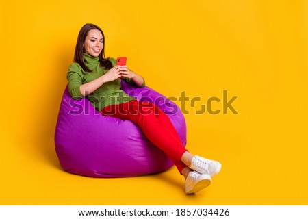 Full length photo of lady sit cozy bean bag comfy chatting telephone wear sweater pants shoes isolated yellow color background