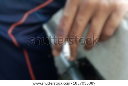 A​ blurry​ picture​ of​ a​ man​ holding​ a​ cigarette.