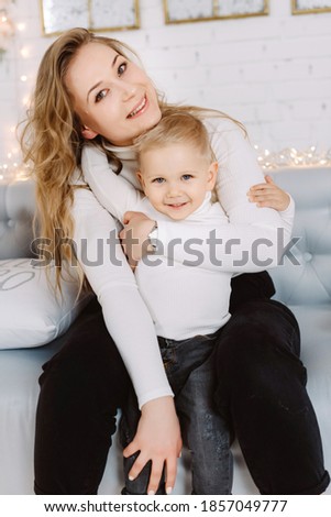 Happy blond hadsome boy and pretty woman enjoying Christmas Time and hugging under Christmas tree