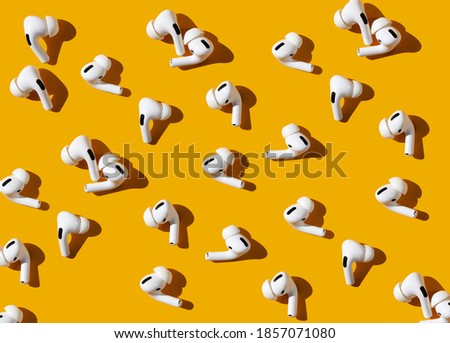 modern wireless headphones for the phone. a lot of plastic air pods on a bright orange background. pattern on the theme of communication and music. flat lay, top view. Royalty-Free Stock Photo #1857071080
