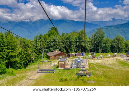 Ski lift in the Red glade in the summer. Tourists climb the mountains. A picturesque view with beautiful clouds over the mountains. Sunny day.