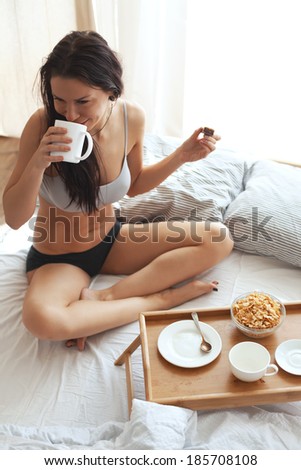 Portrait of 30 years old woman resting in bed with breakfast on a wooden tray at home in morning, still life photo