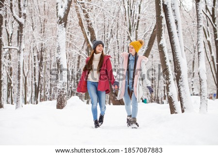 Full body portrait of a young stylish girls walking in winter park 
