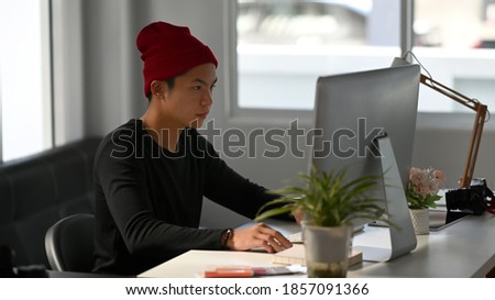 Portrait of freelance graphic designer sitting at his workspace and concentrate to working on computer.