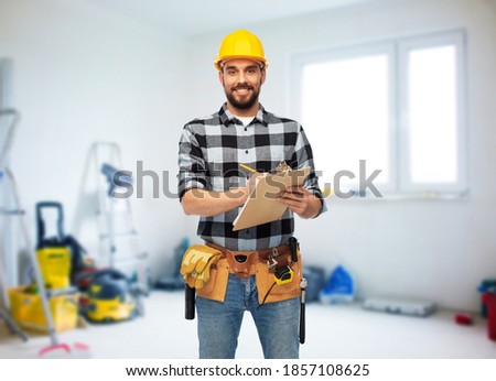 profession, construction and repair concept - happy smiling male worker or builder in helmet with clipboard over room with building equipment background