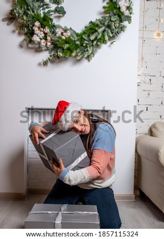Shopping woman holding gift boxes , Christmas and New Year holidays. woman in Christmas Santa hat holding gift box. picture of cheerful santa helper girl with gift box 
