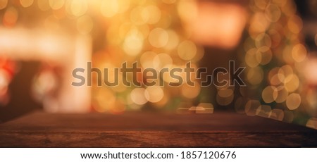 Beautiful blurred Christmas background. In the foreground is a wooden table. In the background there is a Christmas tree and a fireplace.
