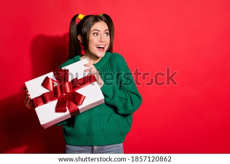 Photo of sweet funny young lady wear green knitted pullover getting present looking empty space isolated red color background