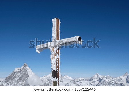 Summit cross at Matterhorn on a sunny day with clear blue sky.