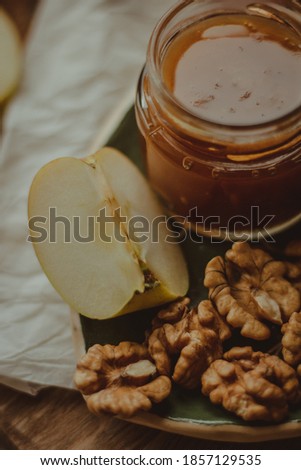 Close-up of honey, nuts and apple on a light background.