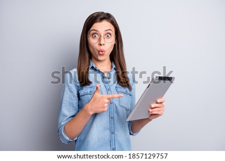 Photo of impressed sweet long hairdo girl pointing tablet wear spectacles blue cloth isolated on grey background