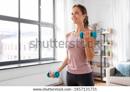 fitness, sport and healthy lifestyle concept - smiling young woman with dumbbells exercising at home Royalty-Free Stock Photo #1857131731