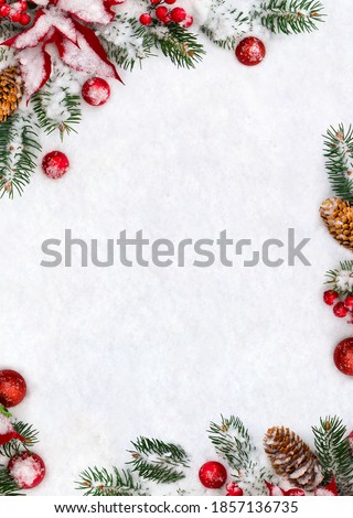 Christmas decoration. Frame of branches christmas tree, flower of red poinsettia, brown natural spruce cones, red ball, red berries on snow with space for text. Top view, flat lay