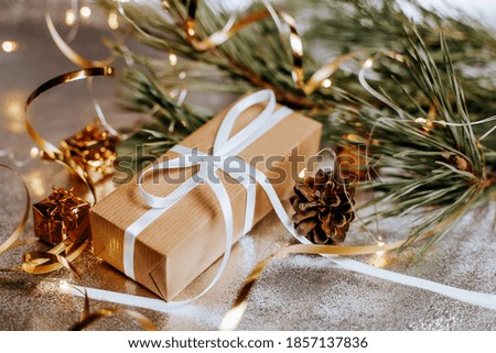 Christmas gifts in lights with pine cones and fir branches in a festive new year atmosphere on a silver background