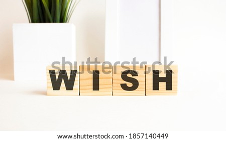 Wooden cubes with letters on a white table. The word is WISH. White background.