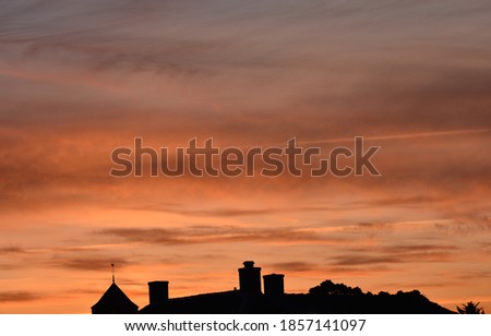 A sunset above a small dutch village. a landscape picture taken of nature. The silhouette of a churche and some houses can be seen.