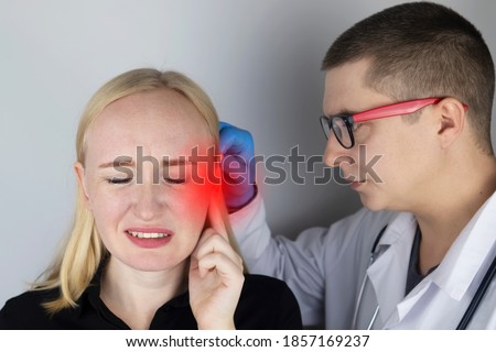 A woman suffers from pain in the ear. The auditory meatus hurts due to otitis media, cerumen plug, ear boil, or trigeminal neuralgia. On examination by a doctor. Royalty-Free Stock Photo #1857169237