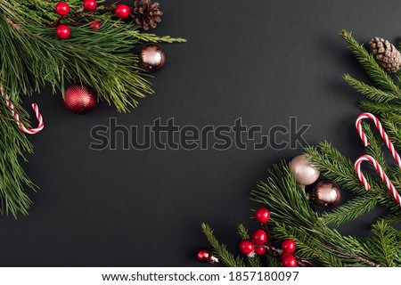 Christmas decoration and xmas tree branches on black background. New Year greeting card. lay, top view, copy space.