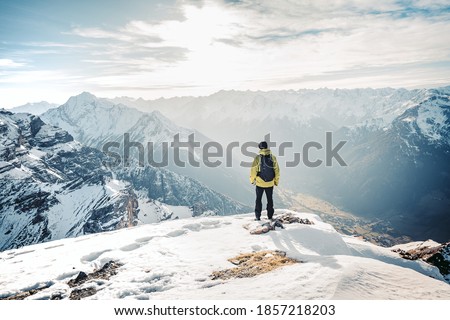 Active people in nature concept. Dressed bright yellow jacket male backpacker enjoying the view as she have mountain walk.Tourist with a backpack and mountain panorama. Adventure concept Royalty-Free Stock Photo #1857218203