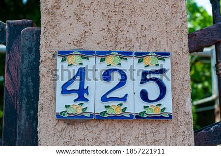 House number plate 425 on a wall. Street number. Address number.