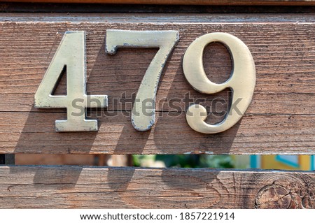 House number plate 479 on a wooden fence. Street number. Address number.