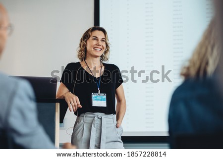 Smiling businesswoman delivering a speech during a conference. Successful business professional giving presentation.