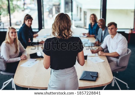 Rear view of a businesswoman addressing a meeting in office. Female manager having a meeting with her team in office boardroom. Royalty-Free Stock Photo #1857228841