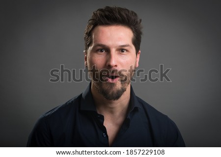 Casual man close up portrait against dark background. Surprised expression.