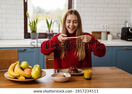 Smiling young woman taking picture on mobile phone of her tasty meal