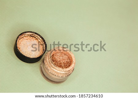 Golden glitter for makeup isolated and open on green background