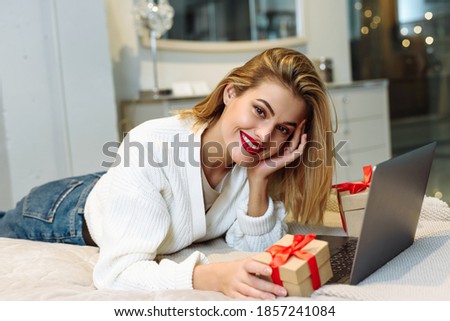 Women wearing white sweater lying on the sofa and using laptop to shopping online at home. christmas online shopping concept
