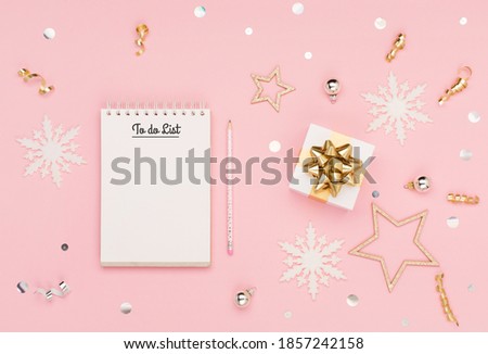 Christmas holiday greeting card. Empty white to do list, gift, snowflakes on pastel pink background. Christmas, winter, new year concept. Flat lay, top view, copy space.